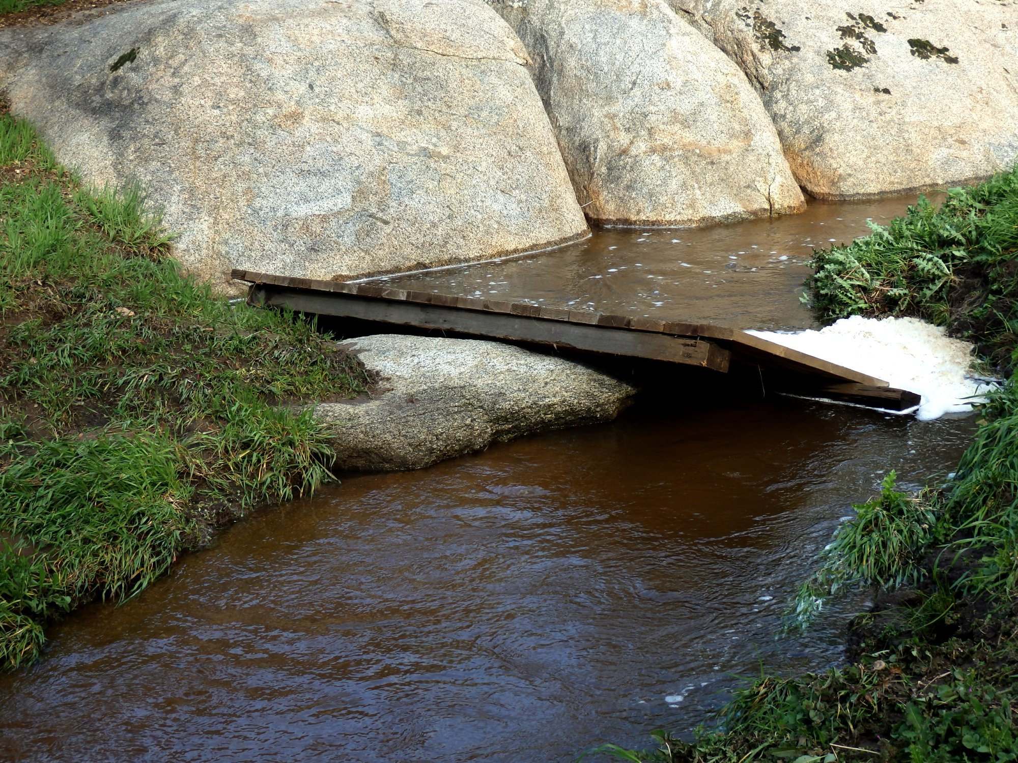 washout bridge caught on boulder in creek x.jpg